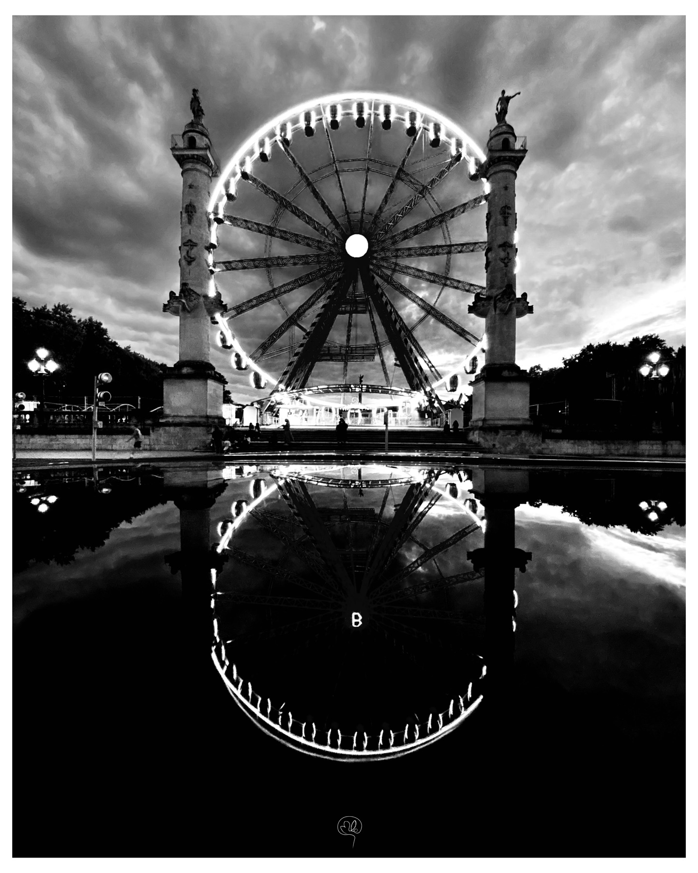 An illuminated Ferris wheel between two columns, reflected in a puddle